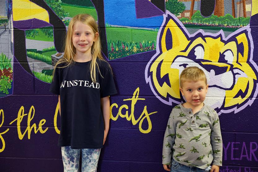 Students stand in front of a mural
